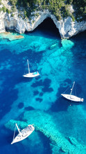 Aerial Drone Bird's Eye View Photo Of Iconic Tropical Rocky Paradise Bay Called Blue Lagoon With Caves And Turquoise Clear Waters Visited By Sail Boats, Island Of Paxos, Ionian, Greece
