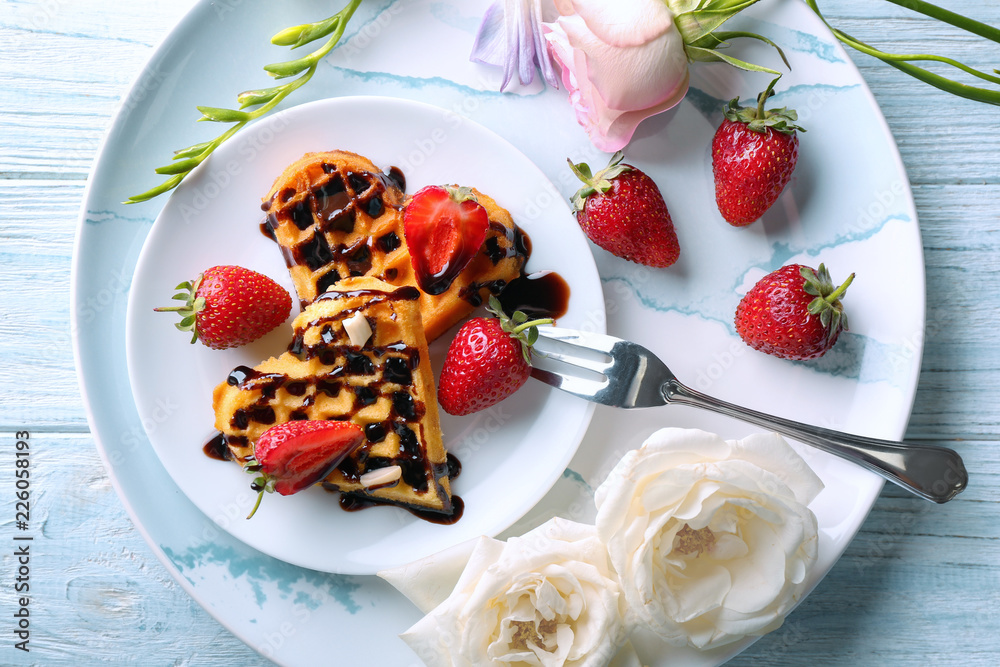 Heart shaped waffles with strawberries and chocolate sauce on plate