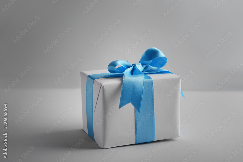 Gift box with blue ribbon on light background