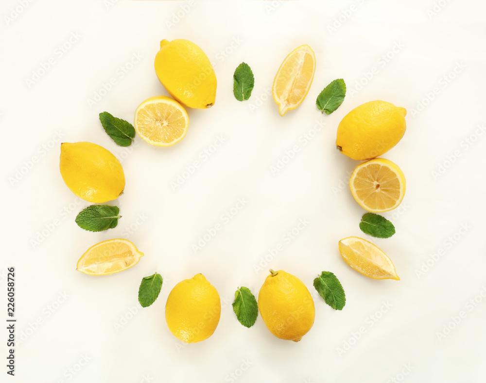 Frame made of fresh lemons and green leaves on white background