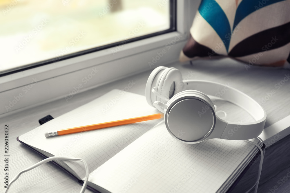 Open notebook and headphones on windowsill