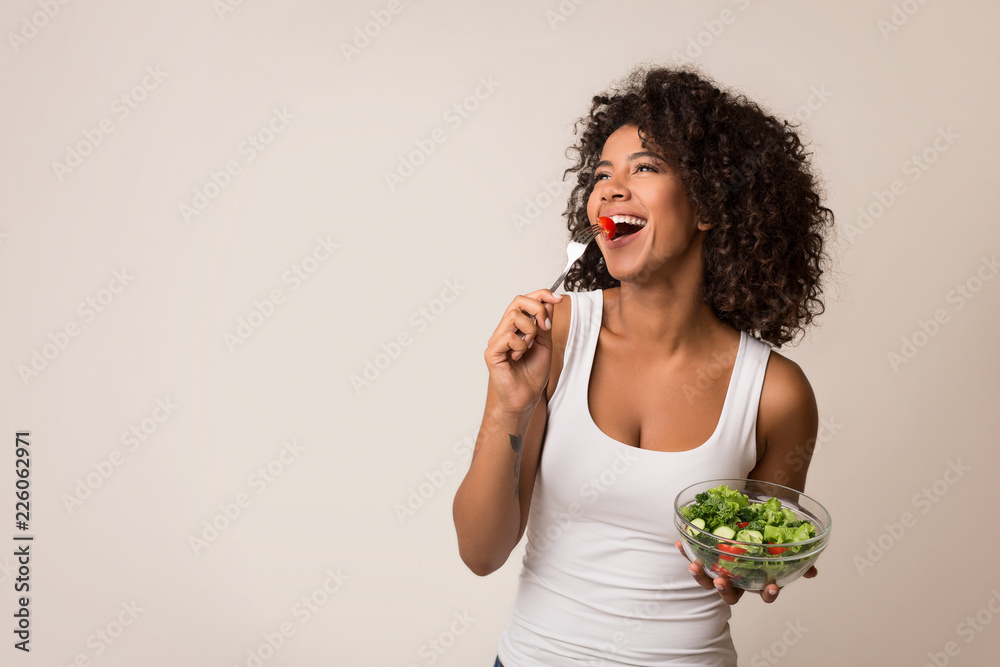 Excited lady eating healthy salad over light background - obrazy, fototapety, plakaty 