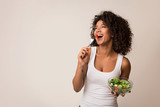 Fototapeta  - Excited lady eating healthy salad over light background