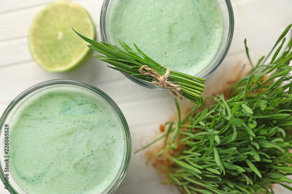 Glasses of wheat grass juice on white wooden table