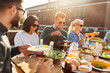 © Syda Productions - leisure and people concept - happy friends eating and drinking at barbecue party on rooftop in summer