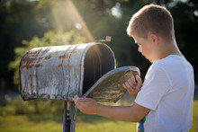 Kid Boy Opening A Post Box And Checking Mail. Kid Waiting For A Letter, Checking Correspondence And Looking Into The Metal Mailbox.