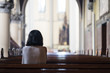 © Creativa Images - Rear view of devout woman praying in the church