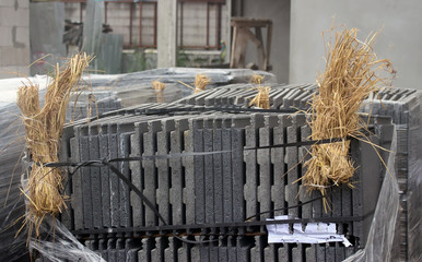 Large pack of building materials on a construction site in south east Asia packed with hay on the corners for cushioning to protect against breakages.