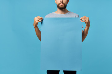 man holding empty sheet of paper blue background place is free