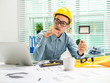 © Phushutter - Young Asian man architect working at working desk about his housing project.