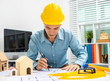 © Phushutter - Young Asian man architect working at working desk about his housing project.