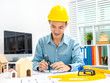 © Phushutter - Young Asian man architect working at working desk about his housing project.