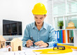 © Phushutter - Young Asian man architect working at working desk about his housing project.