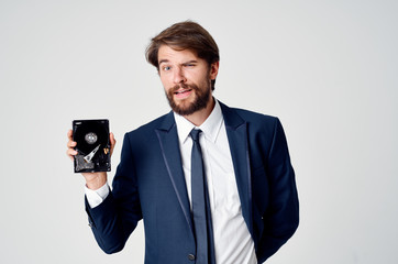 a man with a beard closed one eye in his hand holds a hard drive from the computer