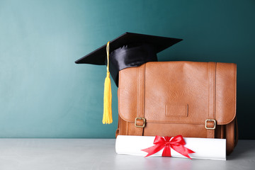 Wall Mural - Graduation hat with briefcase and diploma on table near chalkboard. Space for text