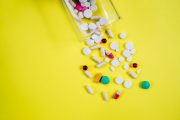 pharmaceutical pill medicine,multivitamin and colorful antibiotic pill medicine on yellow background. pill bottle, glass.Generic prescription medicine drugs.Copy space