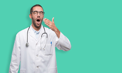 Tired young doctor yawning gesture