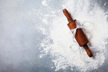 Wall Mural - Bakery background for cooking christmas baking with rolling pin and scattered flour on kitchen table top view.