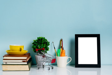 Mock up picture frame, books, office supplies, plant on desk with blue wall