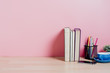 © Satori Studio - Wooden desk table with pink wall with copy space, supplies and coffee mug. Front view workspace and copy space