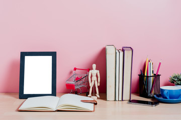 Mock up picture frame, books, office supplies, plant on desk with pink wall