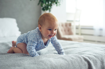 8 month old happy baby boy crawling on bed at home