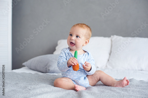 Fototapeta Cute baby boy playing with knitted toy on bed at home