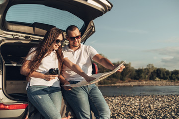 Wall Mural - Happy Couple on Roadtrip into the Sunset in SUV Car