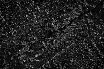 Diagonal crack in black concrete wall - dark grunge background