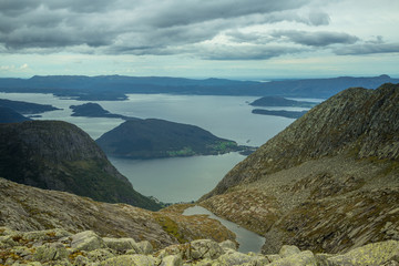 A beautiful autumn landscape of mountains in Folgefonna National park with fjord far in the distance. Fall scenery of southern Norway, Autumn colors in overcast day.