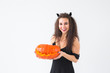© satura_ - Excited happy young woman in halloween costume posing with carved pumpkin in lightroom