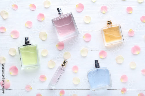 Fotografía Perfume bottles with flower petals on wooden table