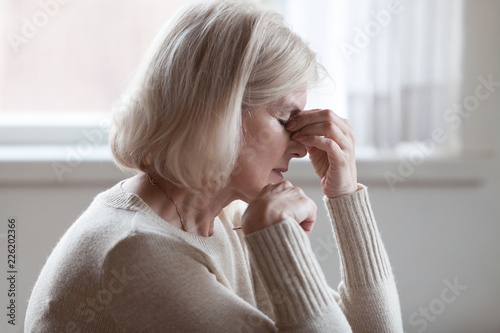 Fotografía Fatigued upset middle aged older woman massaging nose bridge feeling eye strain