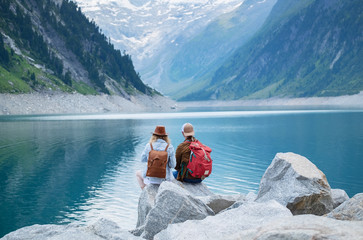 Travelers couple look at the mountain lake. Travel and active life concept with team. Adventure and travel in the mountains region in the Austria