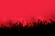© olgavisavi - Red background with a crowd of cheering people at a concert. People with their hands up