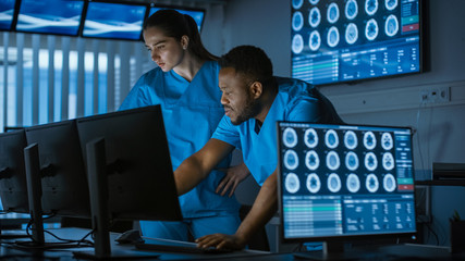 Two Medical Scientists / Neurologists, Talking and  Working on a Personal Computer in Modern Laboratory. Research Scientists Making New Discoveries in the fields of Neurophysiology