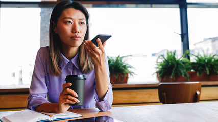 Young businesswoman sitting at cafe and talking on her mobile phone 