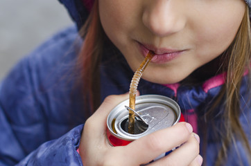 girl drinking a drink through a straw from a can