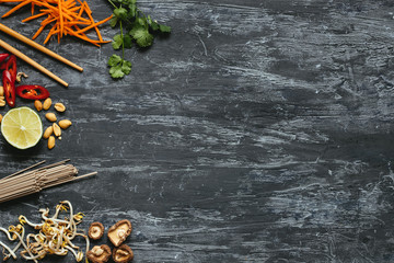 Ingredients for asian dish. Dried asian soba noodles with different ingredients on wooden background with copy space.