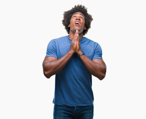 Poster - Afro american man over isolated background begging and praying with hands together with hope expression on face very emotional and worried. Asking for forgiveness. Religion concept.