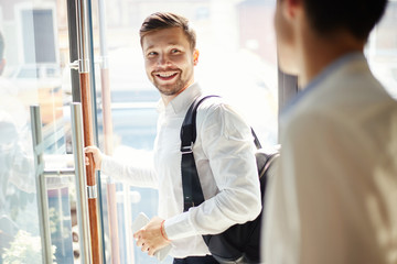 Cheerful businessman leaving cafe and smiling