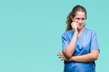 Sticker - Young brunette doctor girl wearing nurse or surgeon uniform over isolated background looking stressed and nervous with hands on mouth biting nails. Anxiety problem.