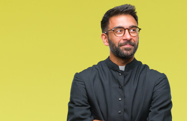 Poster - Adult hispanic catholic priest man over isolated background smiling looking side and staring away thinking.