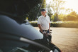 Smiling senior man standing with golf clubs by his car