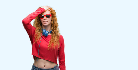 Sticker - Young redhead woman wearing headphones stressed with hand on head, shocked with shame and surprise face, angry and frustrated. Fear and upset for mistake.