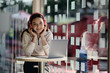 © bongkarn - Young woman listening to music via headphones while sitting at desk