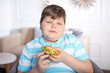 Overweight boy with burger indoors
