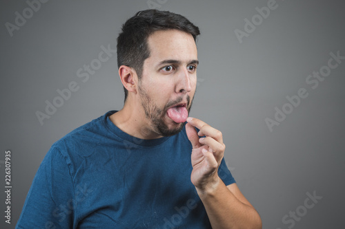 Fotografie, Tablou man pulling something out of his tongue with a face of disgust