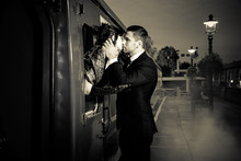 Vintage Couple Embracing And Kissing On Railway Station Platform As Train Is About To Depart