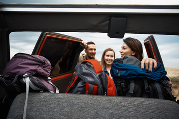 Wall Mural - Delighted young group of tourists enjoying their active weekend while getting their backpacks